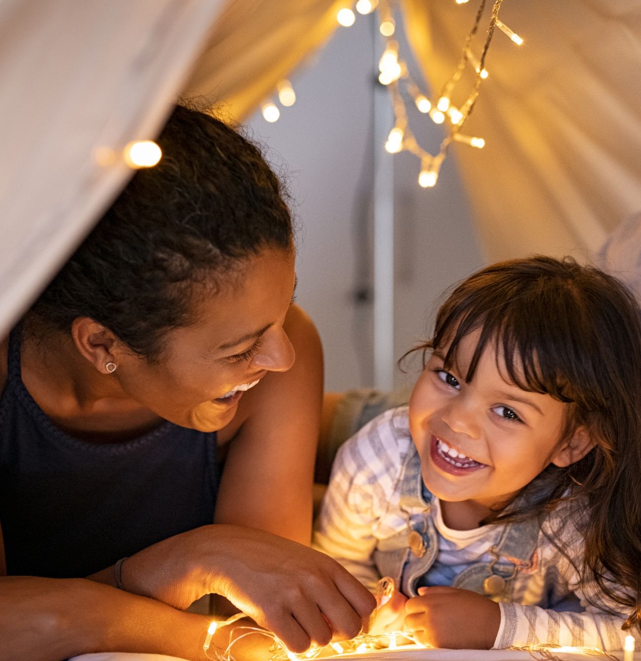 Allara, Eglinton mother and daughter smiling while laying in teepee.