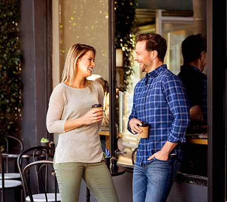 Arcadia, Officer man and woman standing in front of coffee shop drinking take away coffees.