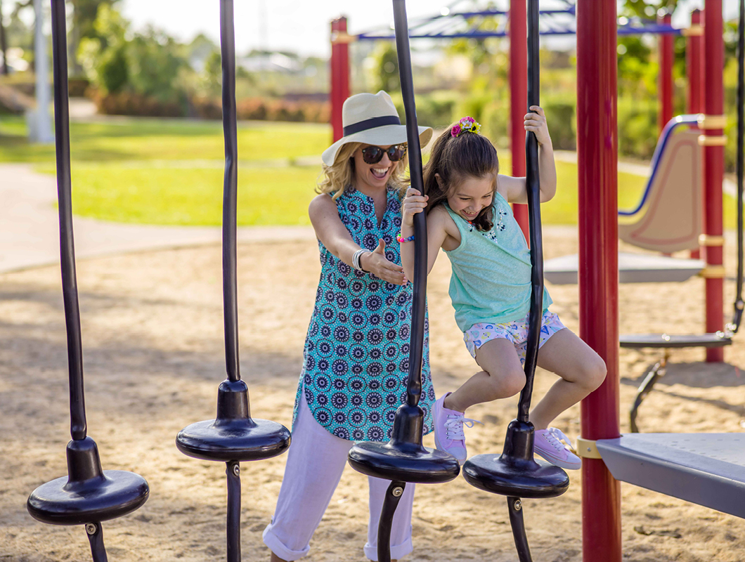 Smithfield Village, Smithfield mother helping young daughter on local park play equipment.
