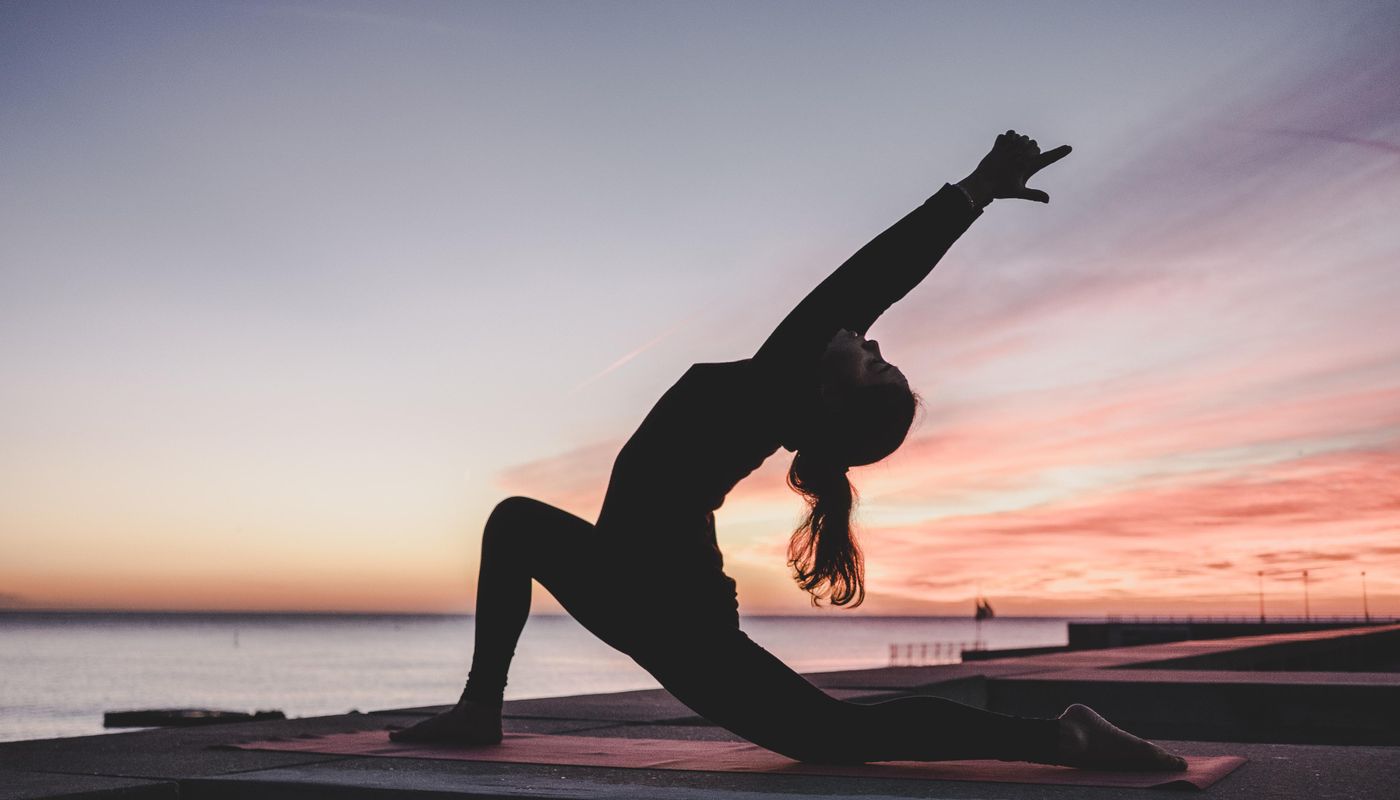 Eden Beach, Jindalee, young woman completing a yoga pose in front of the water