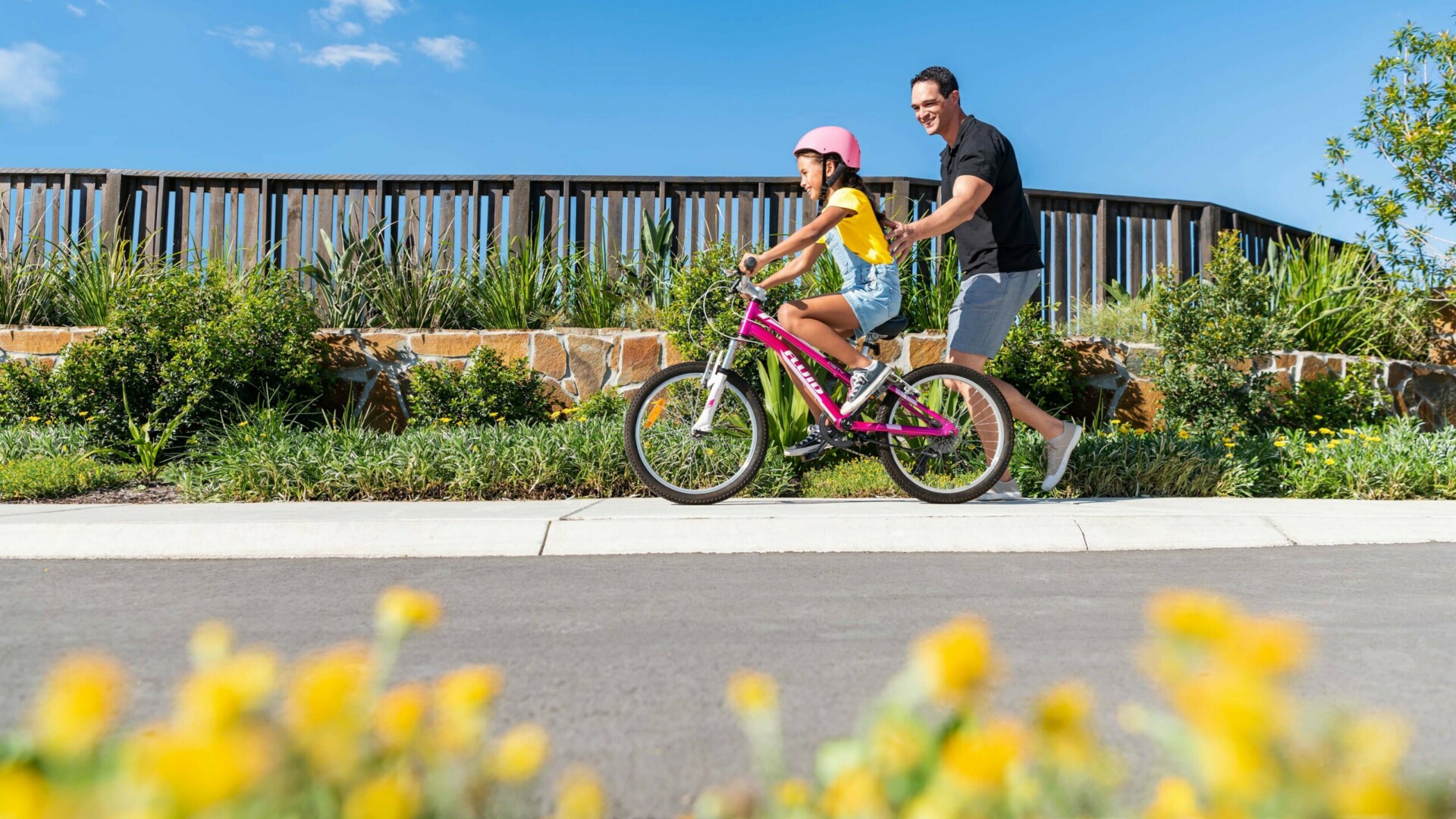 Ripley Valley, Ripley father helping young daughter ride bike along footpath.