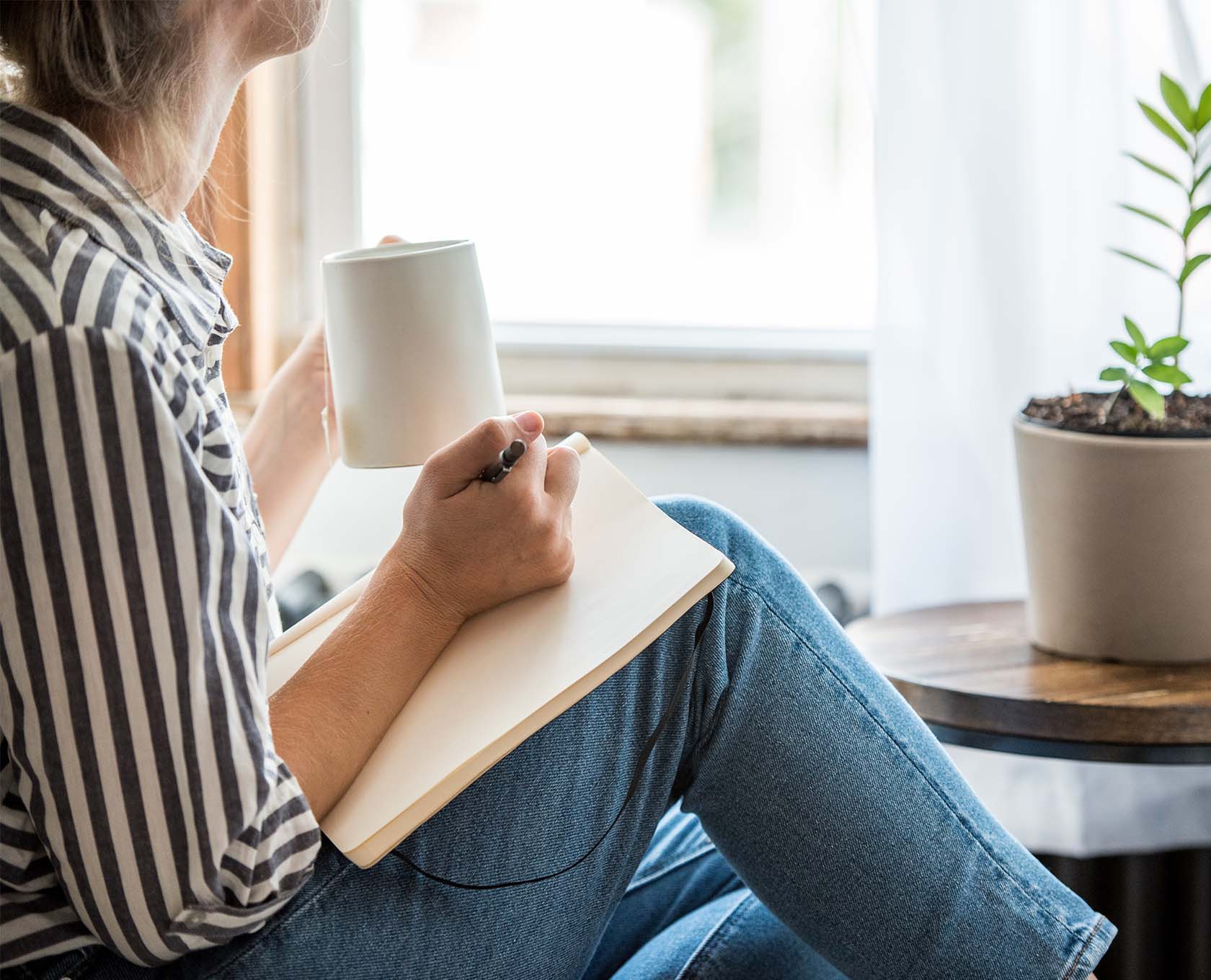 Woman writing down notes and drinking a coffee