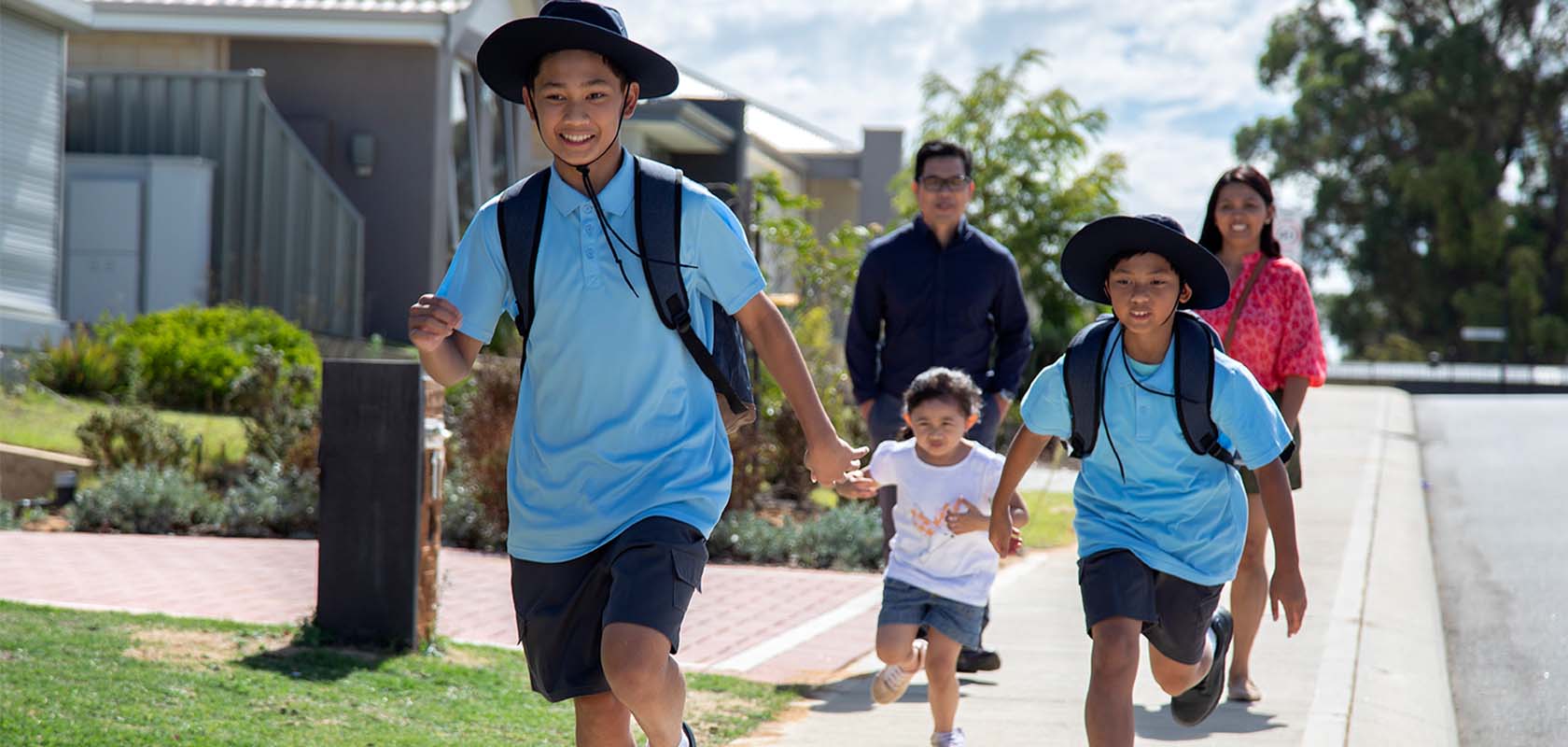 Children running to school with parents behind them