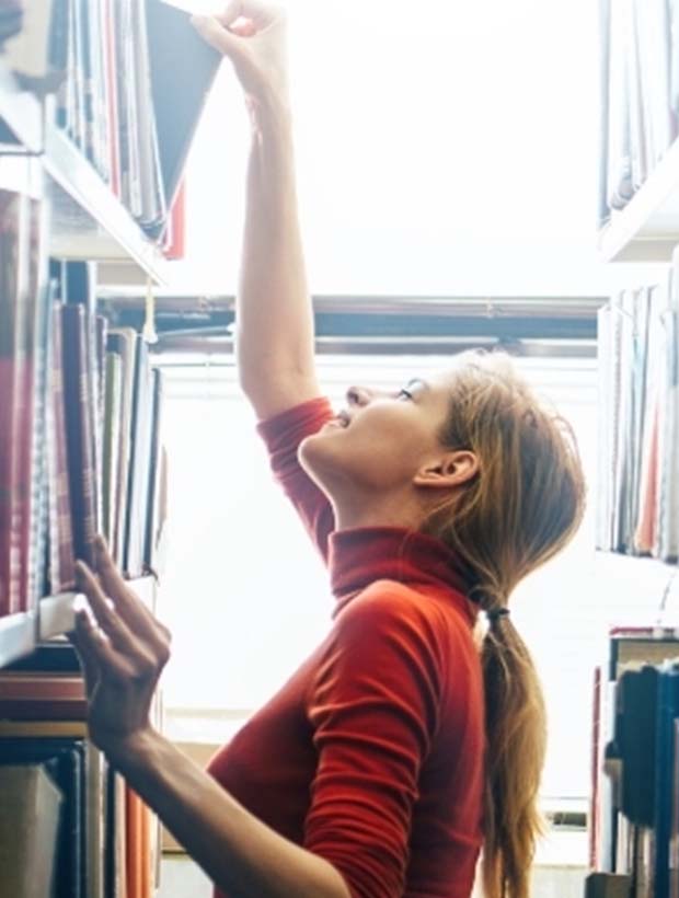 Young female choosing a book in the library