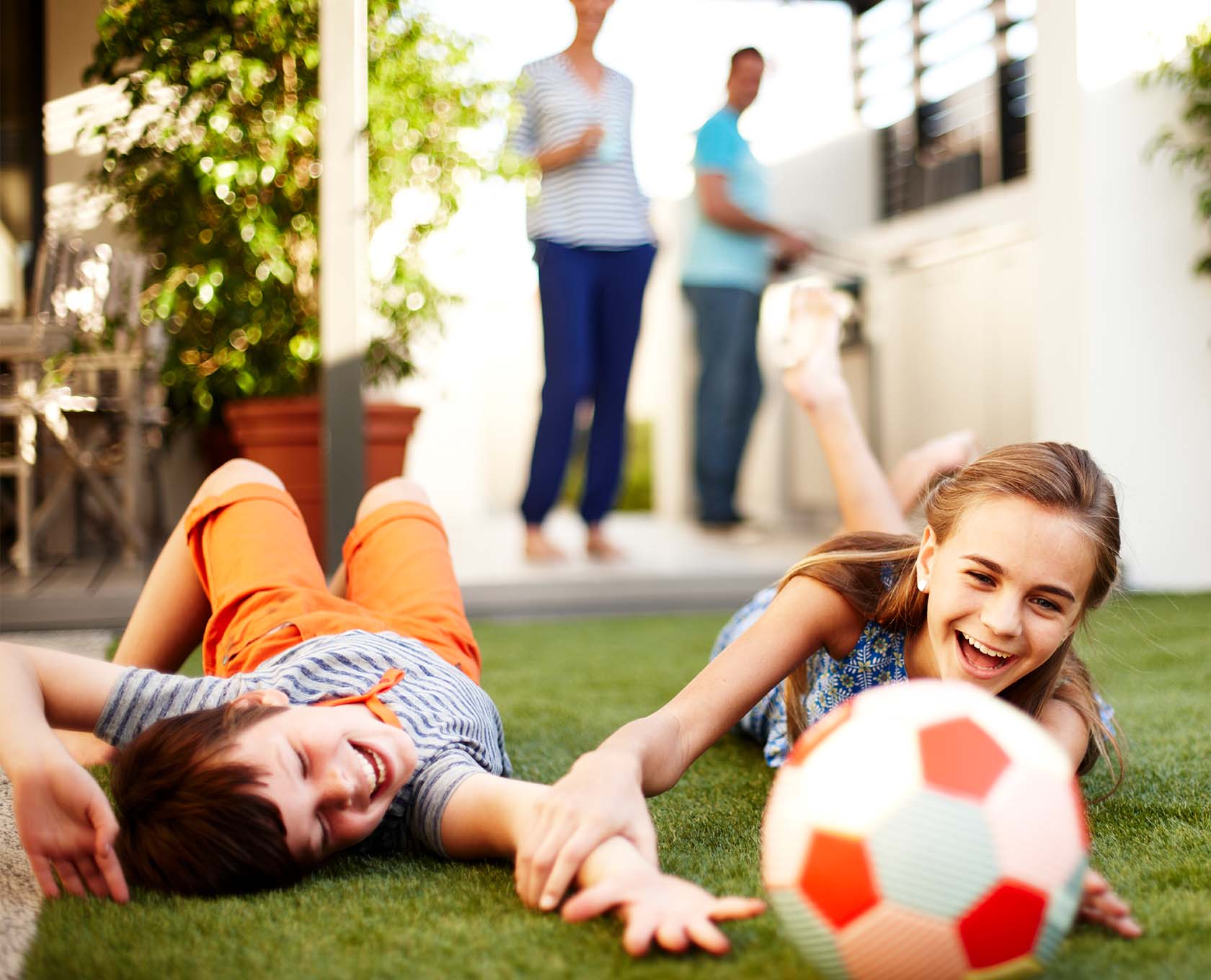 Young children playing with soccer ball in the backyard