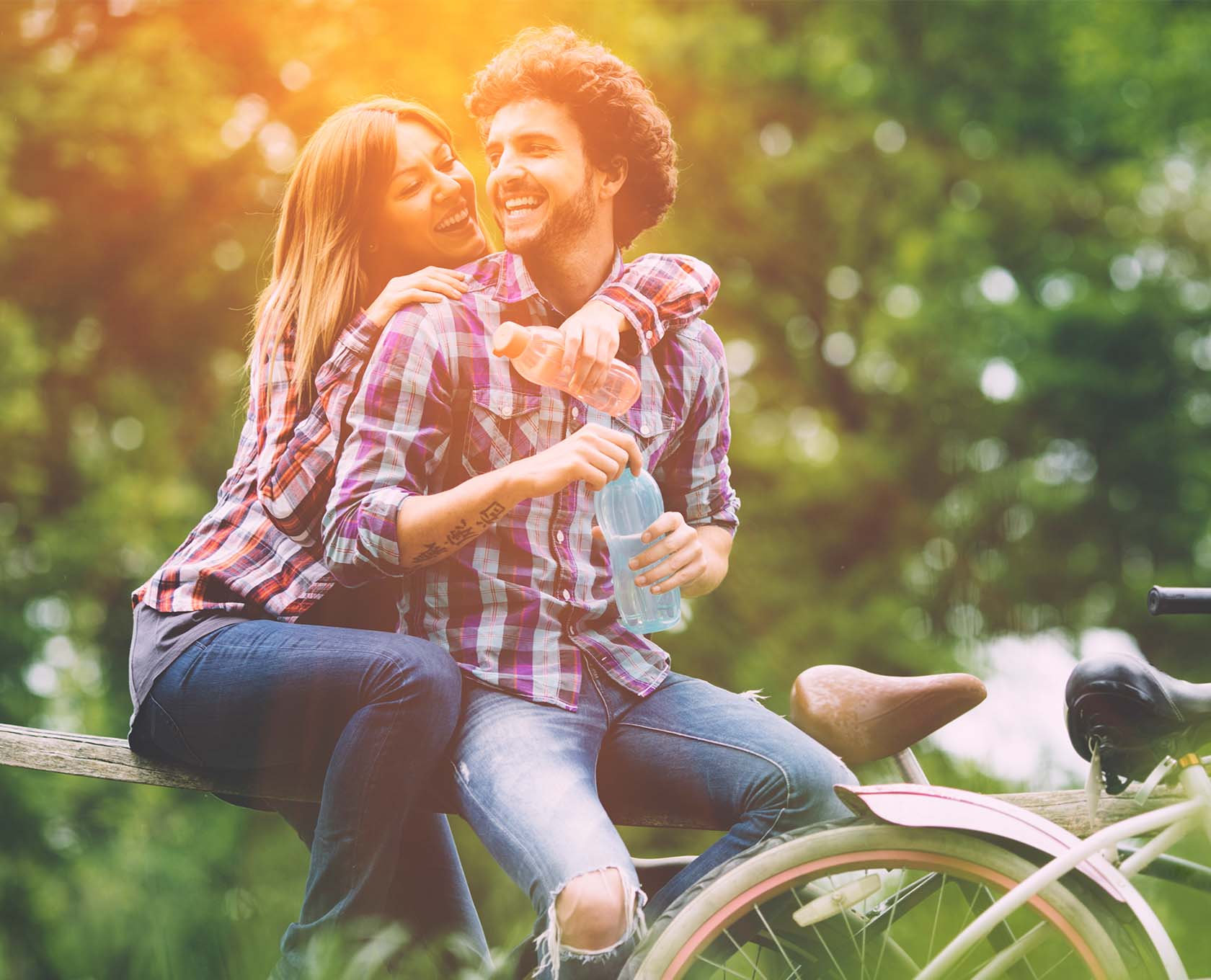 Young couple sitting on the fence laughing