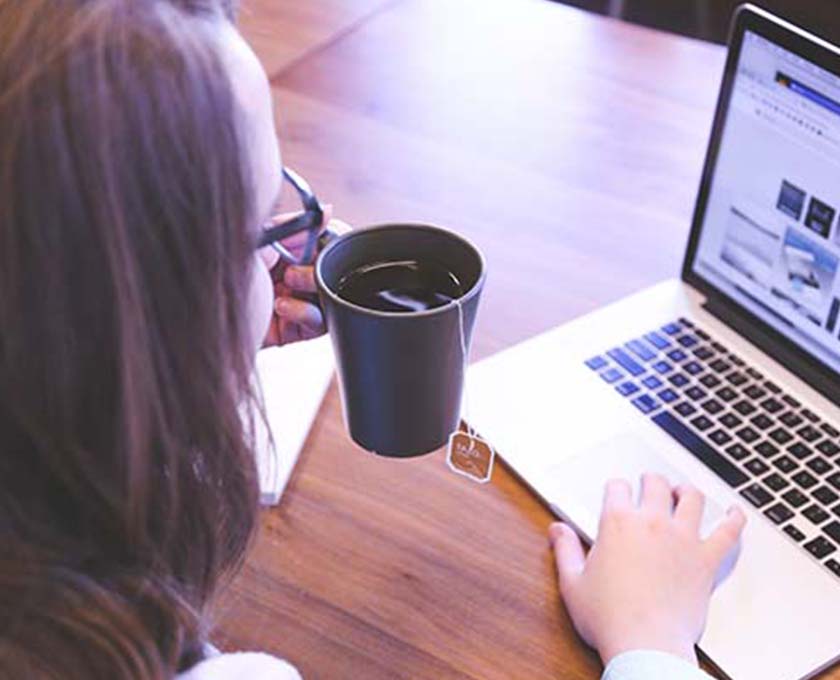 Young woman sipping a tea on her laptop