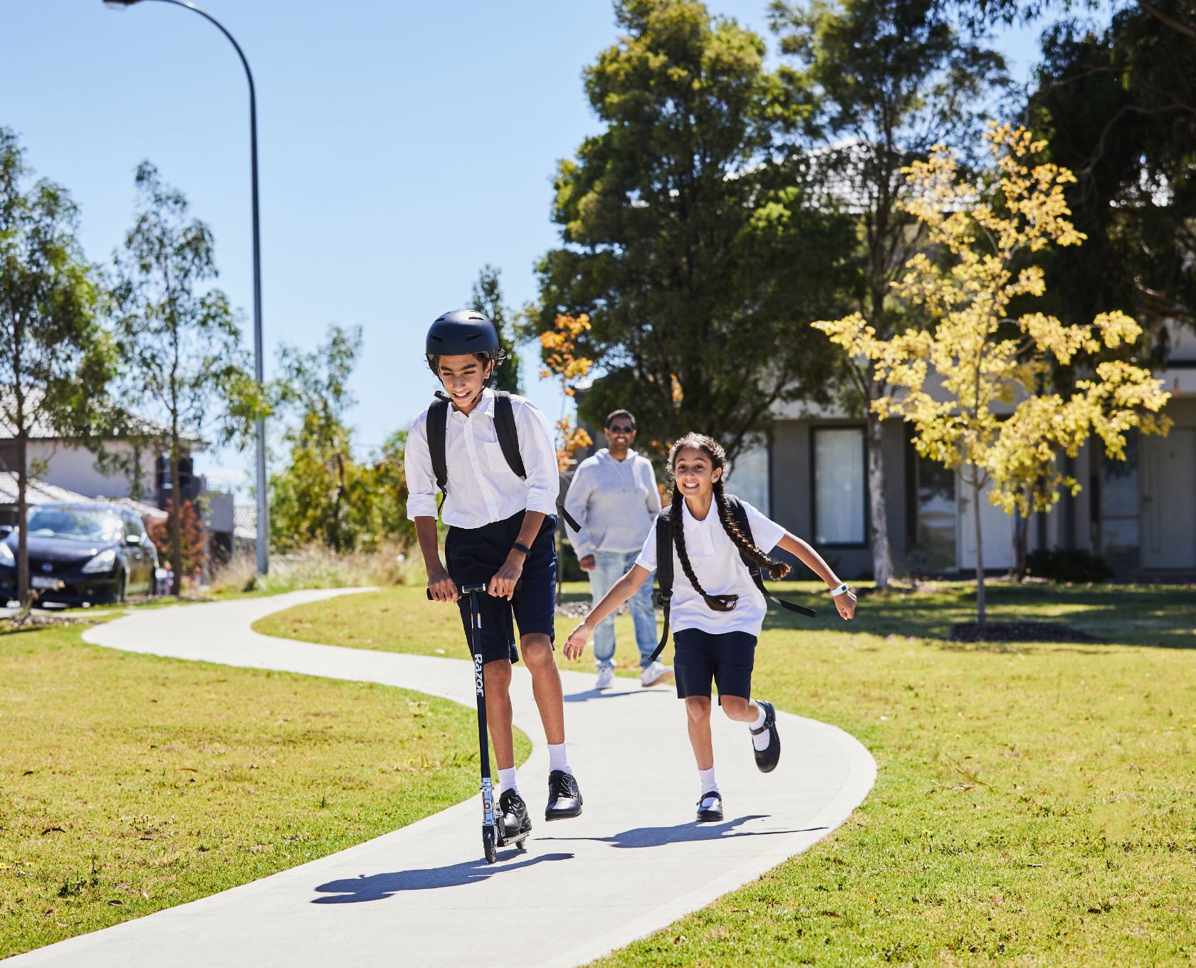 Maple Grove, Pakeham school kids riding scooter and running with father walking not too far behind.